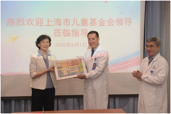 上海市儿童基金会名誉理事长杨定华（左一）向院长孙锟赠送儿童抗疫画作