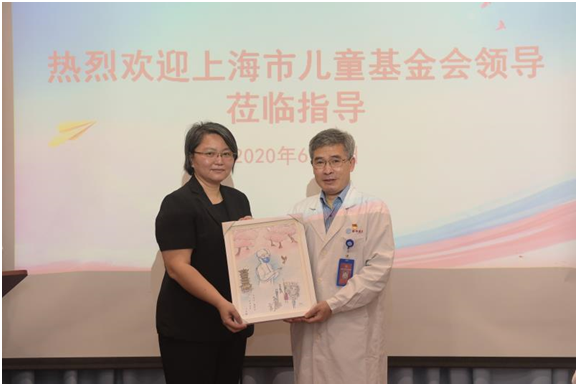 上海市妇女联合会副主席王剑璋（左一）向党委书记唐国瑶赠送儿童抗疫画作